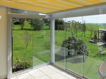 Aussicht aus einem Glashaus mit Glasschiebeelementen und innenliegendem Sonnenschutz